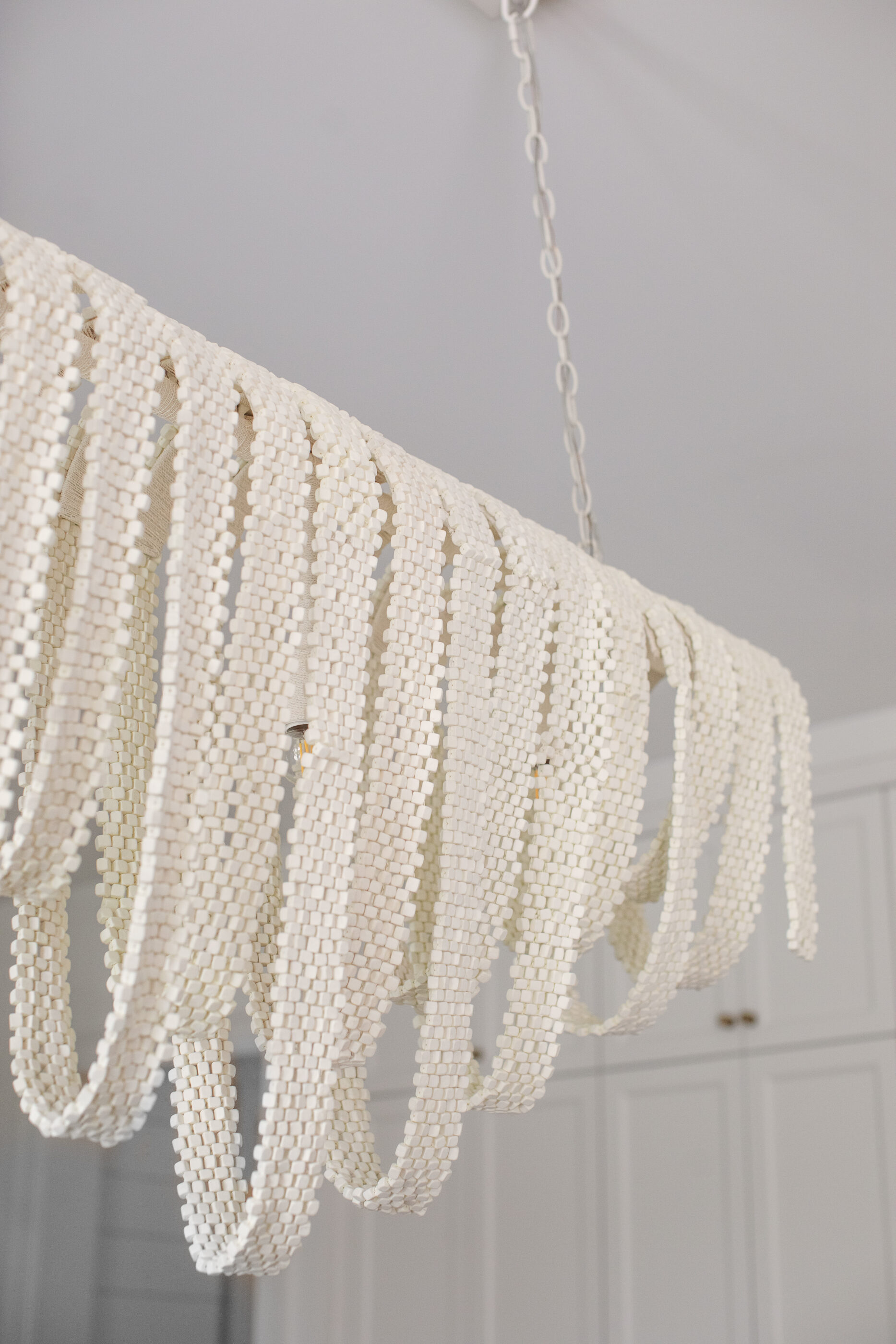 “Lowcountry luxury interior design by Megan Molten featuring coastal modern style, custom upholstery, woven textures, and statement lighting in a serene Kiawah home. Soft blues, neutrals, and sandy tones create an airy atmosphere across kitchen, living room, bedroom, bathroom, and poolside spaces