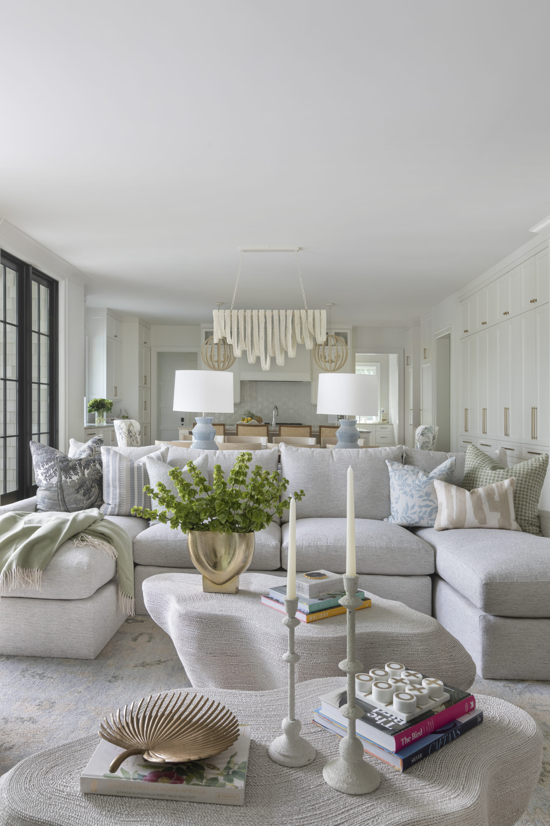 “Lowcountry luxury interior design by Megan Molten featuring coastal modern style, custom upholstery, woven textures, and statement lighting in a serene Kiawah home. Soft blues, neutrals, and sandy tones create an airy atmosphere across kitchen, living room, bedroom, bathroom, and poolside spaces