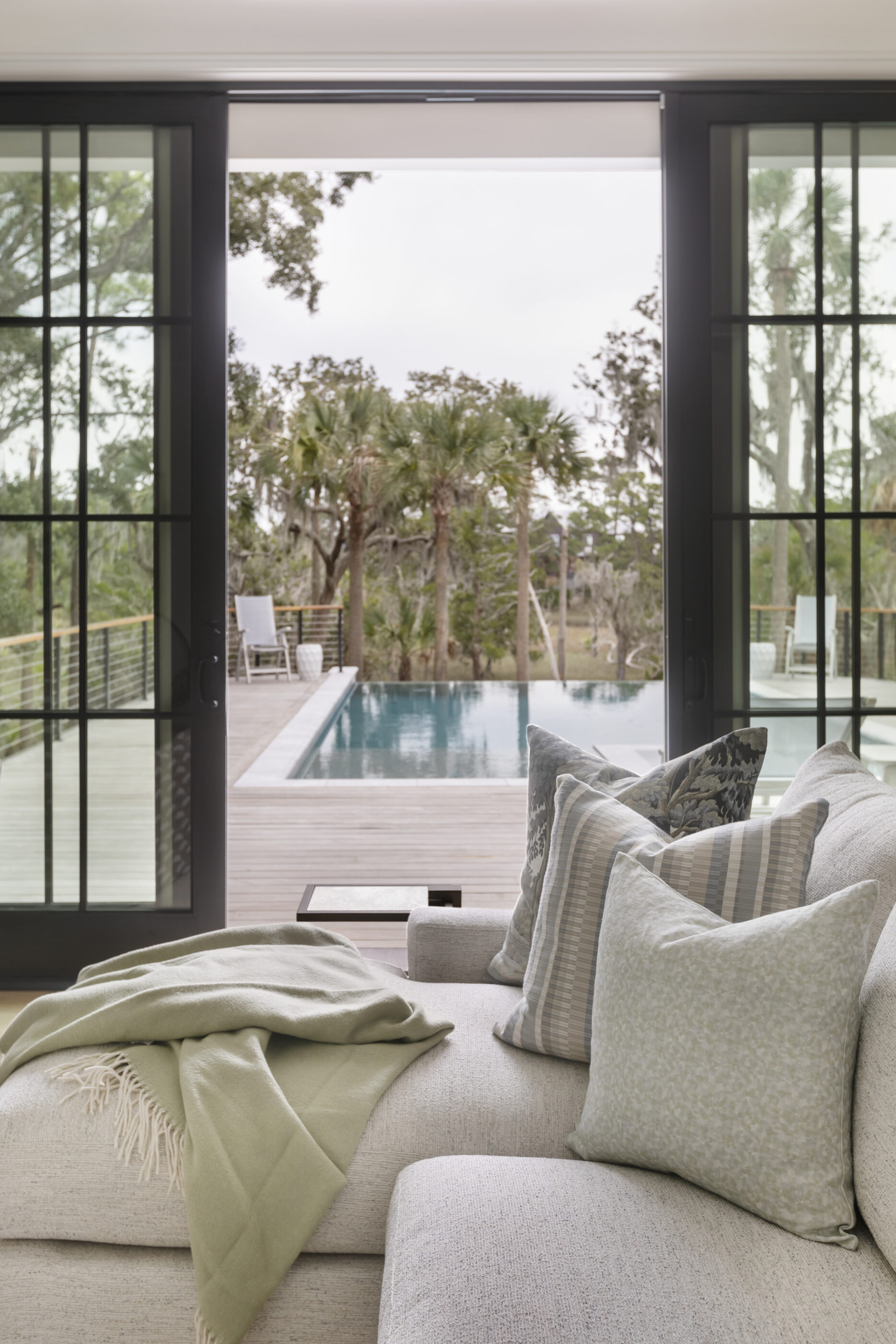 “Lowcountry luxury interior design by Megan Molten featuring coastal modern style, custom upholstery, woven textures, and statement lighting in a serene Kiawah home. Soft blues, neutrals, and sandy tones create an airy atmosphere across kitchen, living room, bedroom, bathroom, and poolside spaces