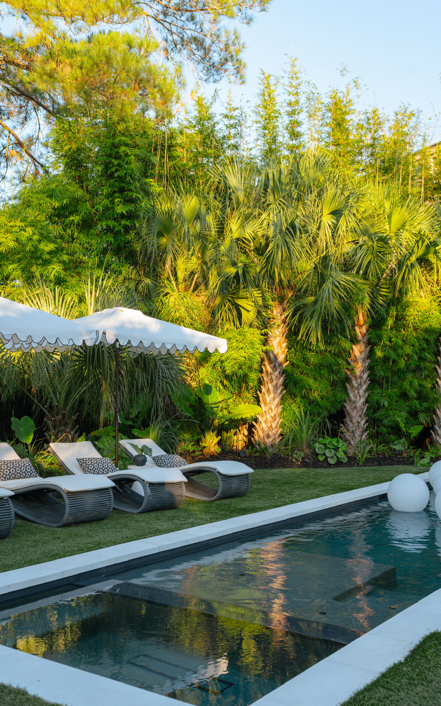 Luxury backyard pool with lounge chairs, lush tropical landscaping, and outdoor seating for a private resort-style atmosphere