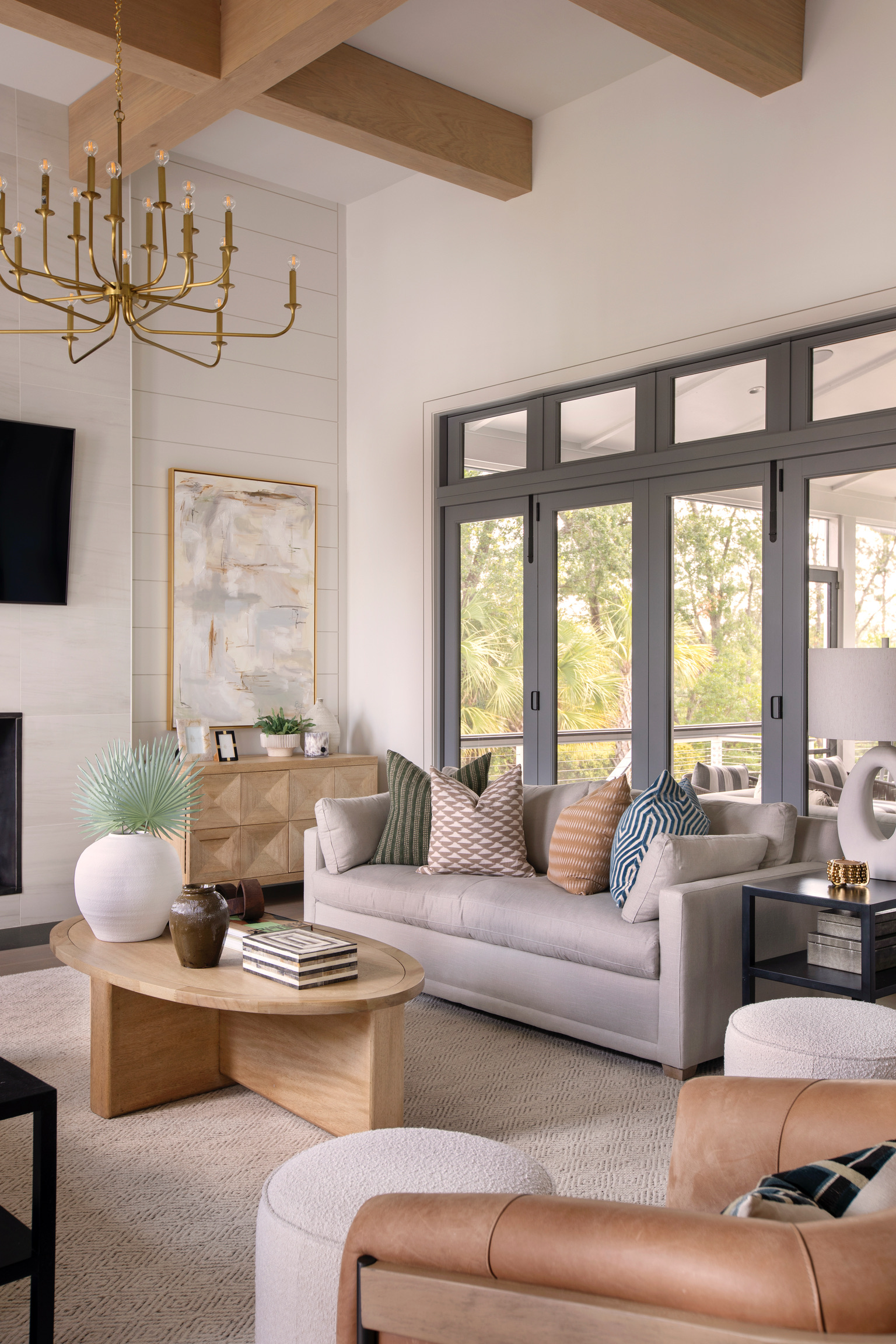 Coastal living room with exposed wood beams, neutral furniture, layered textures, and natural light for a luxury resort-inspired design