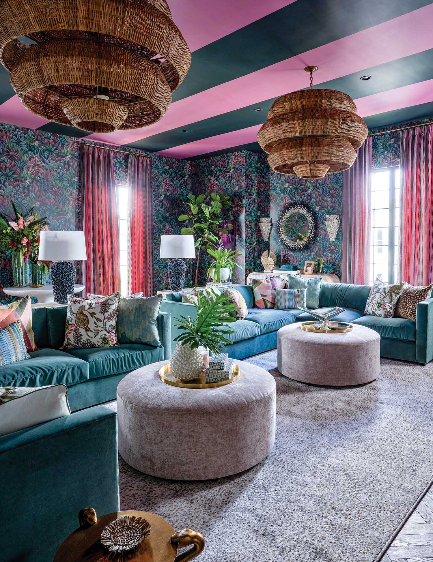 Bold eclectic living room with teal velvet sectional, tropical wallpaper, pink striped ceiling, woven pendant lights, and layered textures creating a vibrant luxury space.