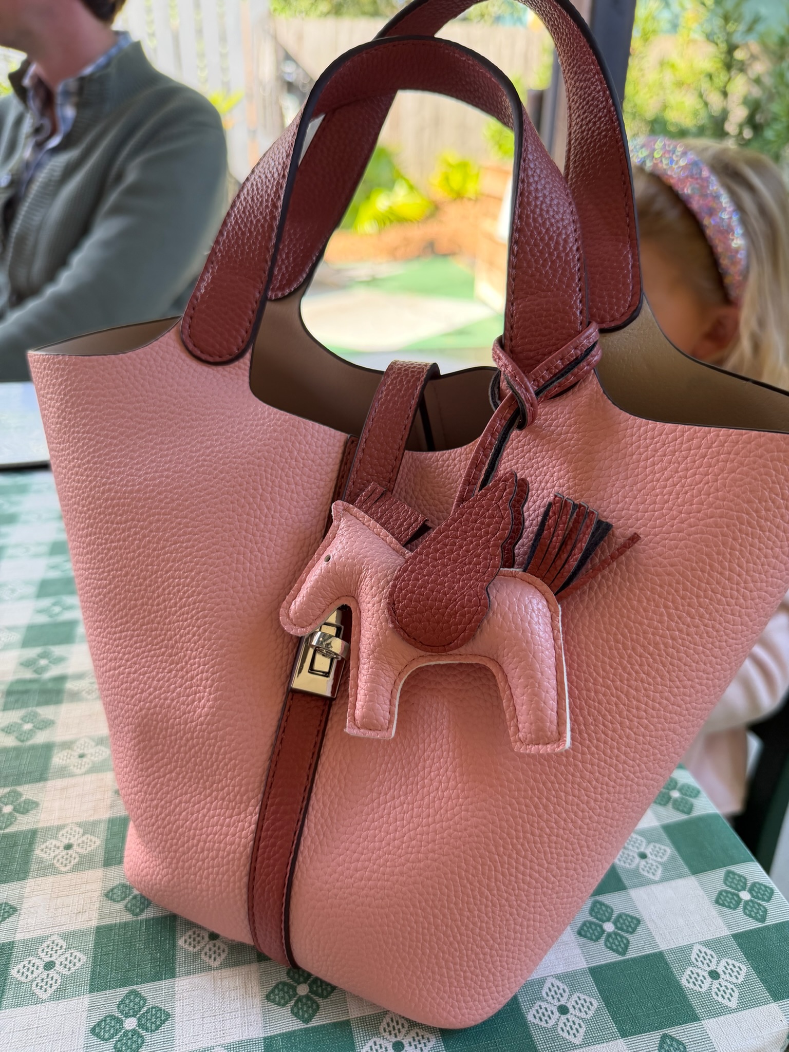 Close-up of a pink designer-inspired Amazon handbag with textured leather detail and playful charm.