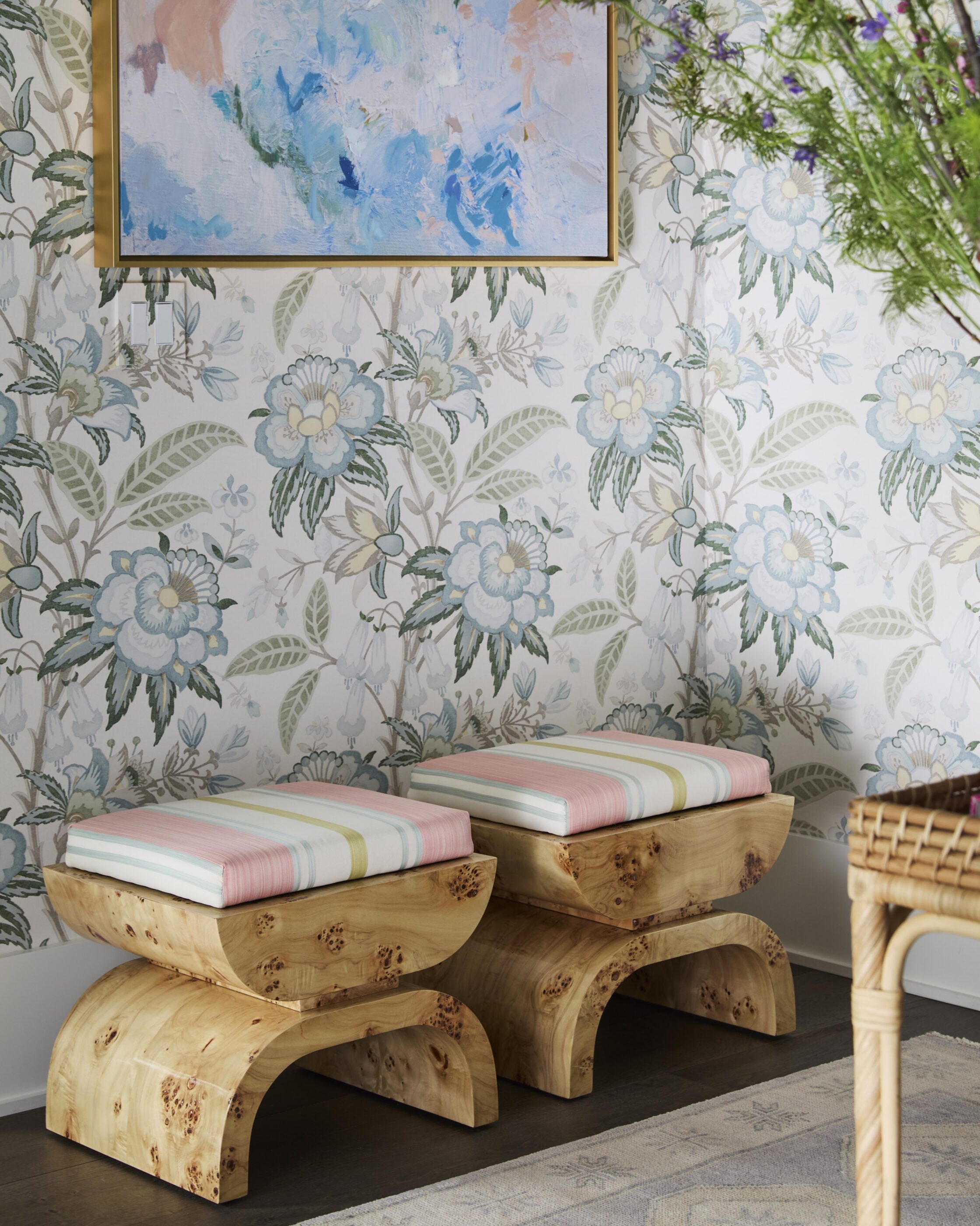 Entryway with floral wallpaper, open double doors, gold botanical chandelier, woven console table, and natural wood bench.