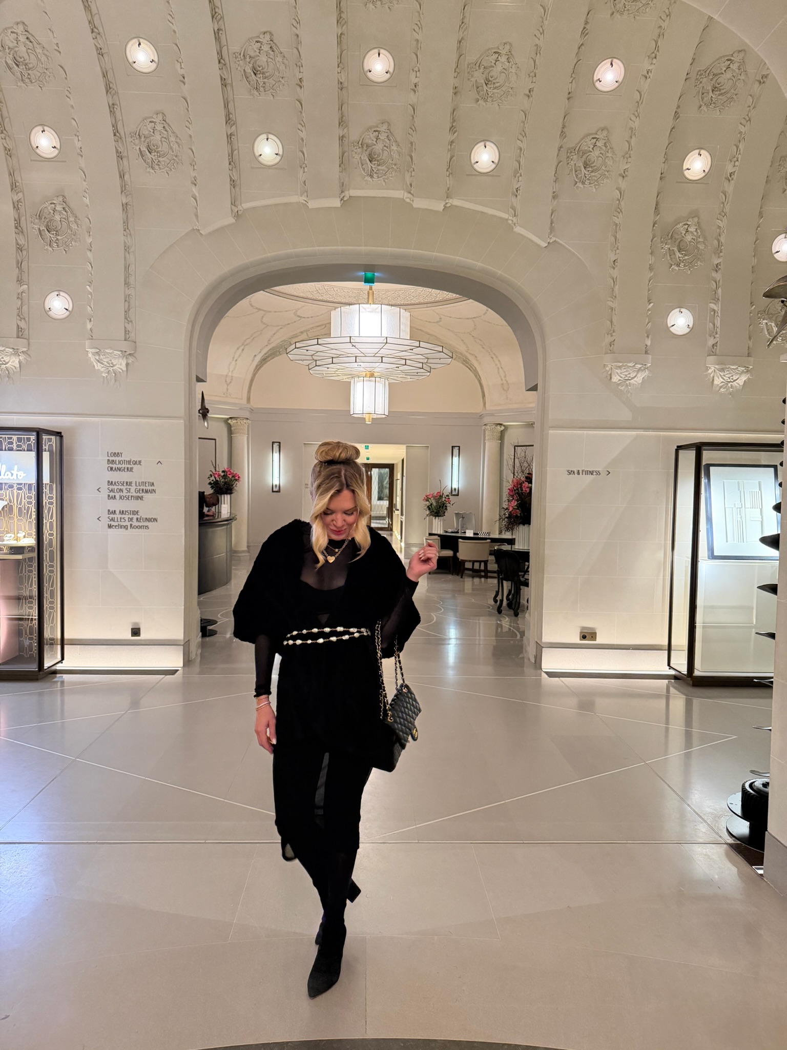 Megan Molten wearing an all-black evening travel outfit with layered jewelry and a Chanel handbag while in Paris